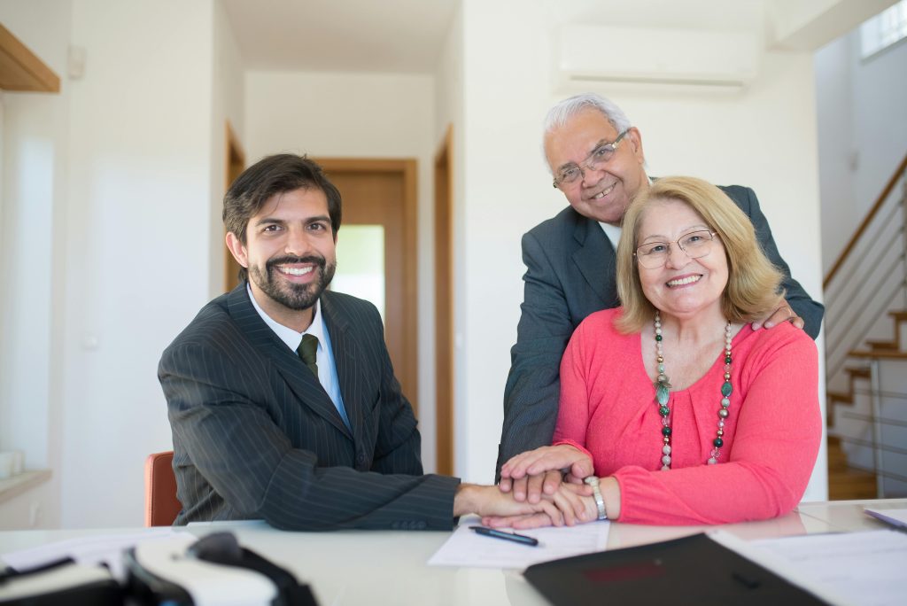 Smiling senior couple meeting with a professional advisor in a bright indoor setting.